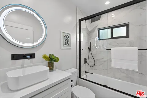 a bathroom with a granite countertop toilet sink and mirror