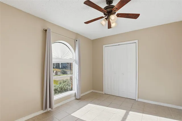 an empty room with fan and windows