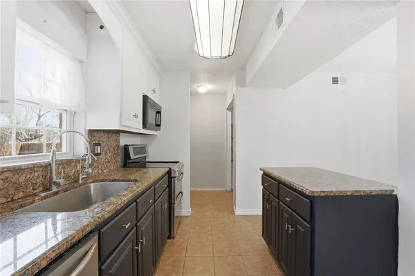 a kitchen with granite countertop a sink stove and cabinets
