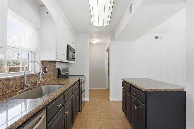 a kitchen with granite countertop a sink stove and cabinets