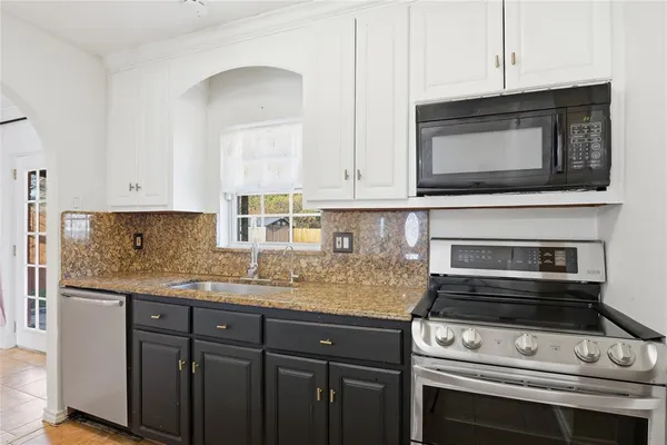 a kitchen with granite countertop a stove microwave and sink