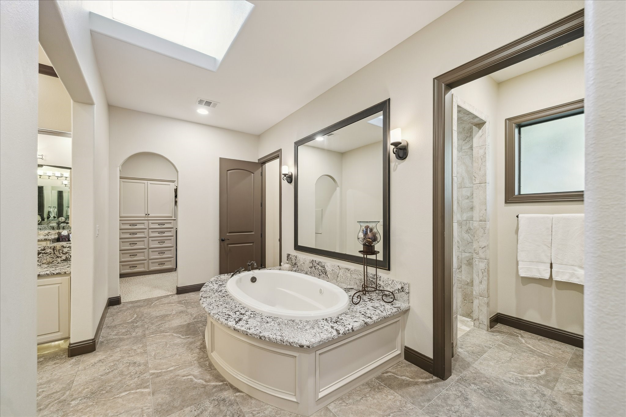 11 Willowcreek Ranch Road Tomball, TX 77377 - Photo 42 of 49 The large soaking tub is a focal point with the oversized shower beyond. The primary features two separate primary closets. One may be seen through the opening with convenient built-in drawers and cabinetry.