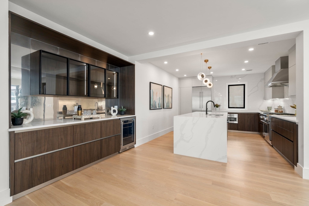 116 Thorndike Street, Unit 2B Brookline, MA 02446 - Photo 12 of 33 a large white kitchen with kitchen island a sink a counter top space stainless steel appliances and cabinets