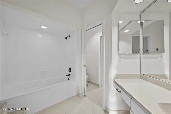 a bathroom with a tub shower vanity and a sink