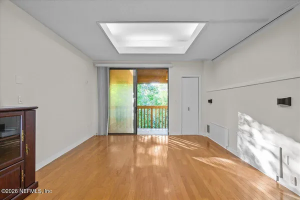 a view of empty room with wooden floor and fan