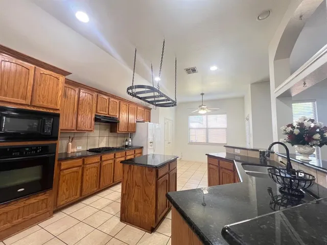 a kitchen with granite countertop a stove a sink a dining table and chairs