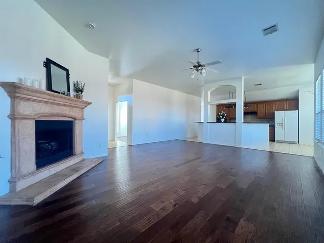 an empty room with wooden floor a fireplace and windows