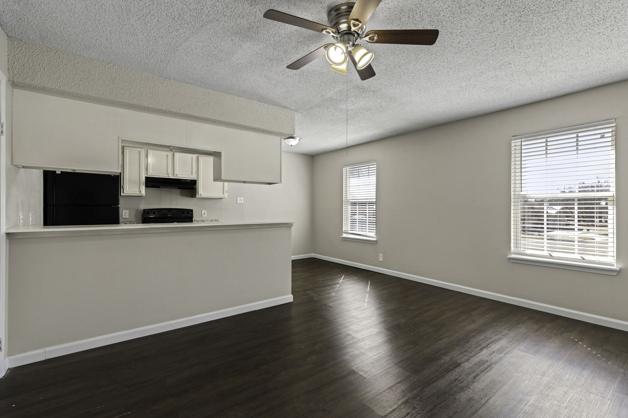 6110 Wheless Cove, Unit F Austin, TX 78723 - Photo 5 of 12 Unfurnished living room featuring a textured ceiling, ceiling fan, and dark wood-style floors