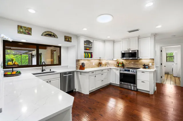 a kitchen with stainless steel appliances a refrigerator and wooden floor