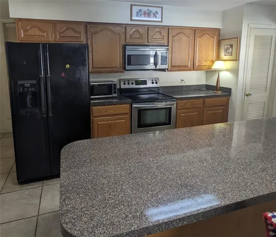 a kitchen with stainless steel appliances granite countertop a refrigerator a stove and a sink