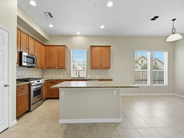 a large kitchen with stainless steel appliances granite countertop a stove top oven a sink dishwasher a dining table and chairs