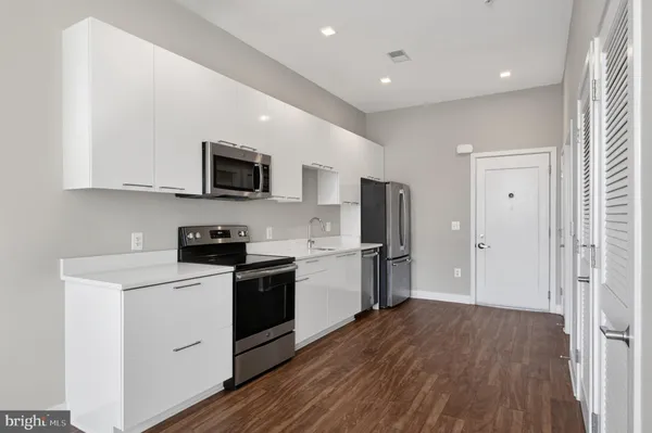 a kitchen with a refrigerator a stove top oven a sink and dishwasher with wooden floor