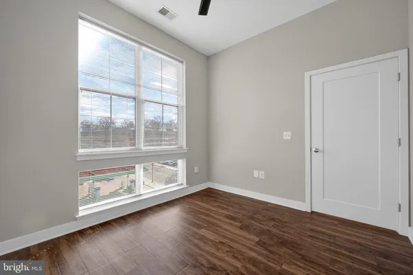 an empty room with wooden floor and windows