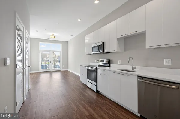 a kitchen with stainless steel appliances a sink cabinets and wooden floor
