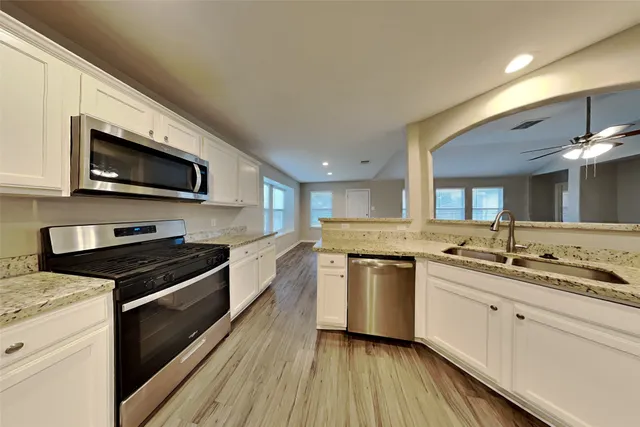 a kitchen with stainless steel appliances granite countertop a stove a sink and a microwave