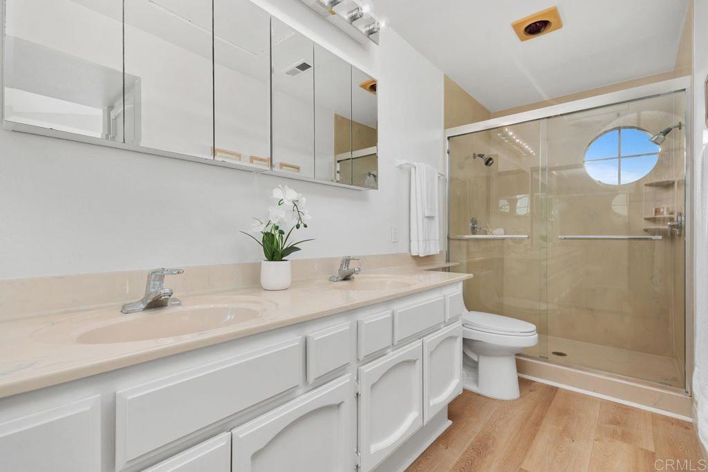 7013 Lavender Way Carlsbad, CA 92011 - Photo 22 of 51 a bathroom with a granite countertop sink a toilet a mirror and shower
