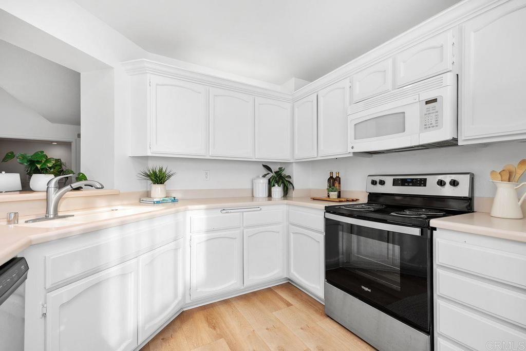7013 Lavender Way Carlsbad, CA 92011 - Photo 9 of 51 a kitchen with granite countertop white cabinets stainless steel appliances and a sink