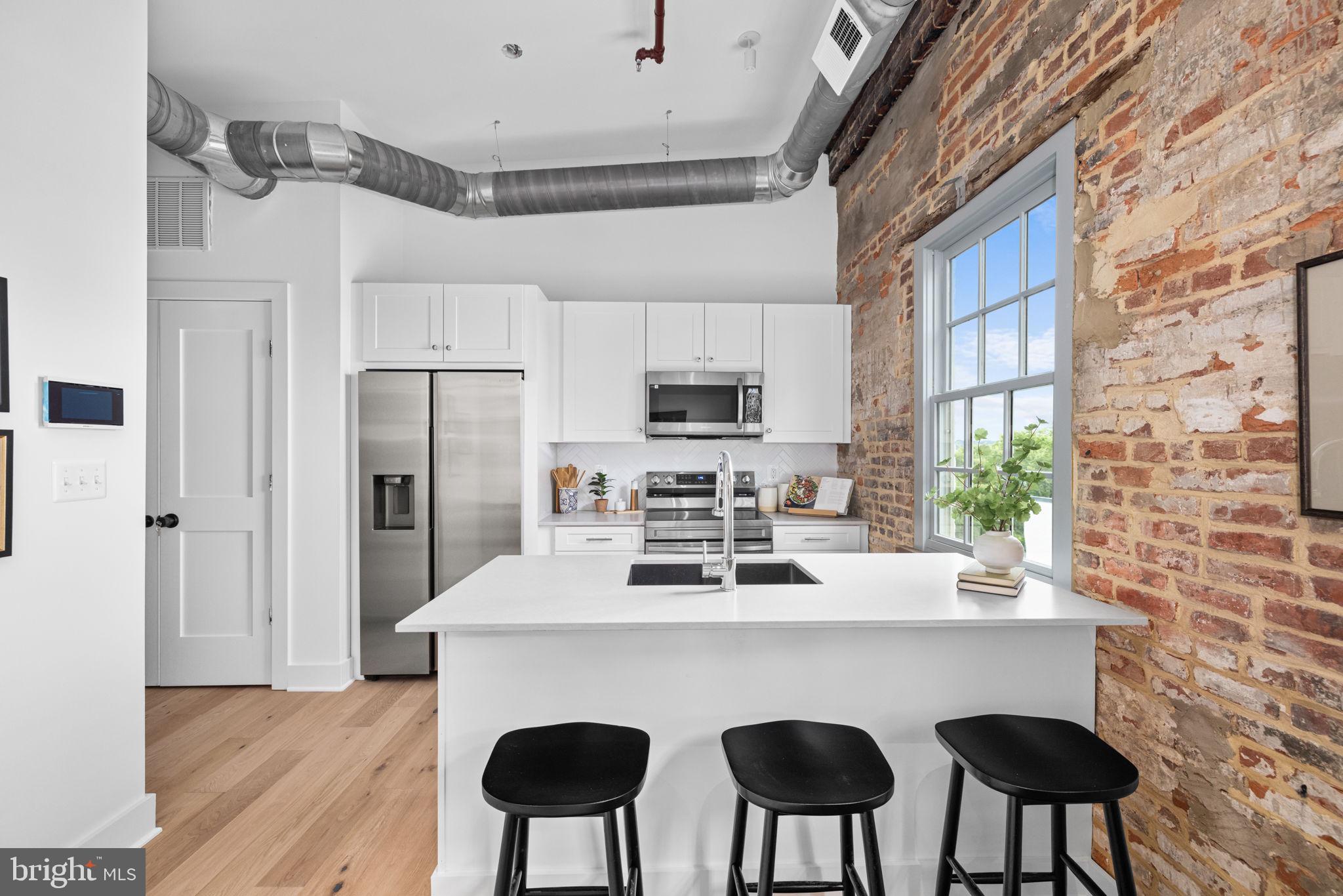 901 King Street, Unit 401 Alexandria, VA 22314 - Photo 2 of 32 a kitchen with stainless steel appliances a dining table chairs refrigerator and sink