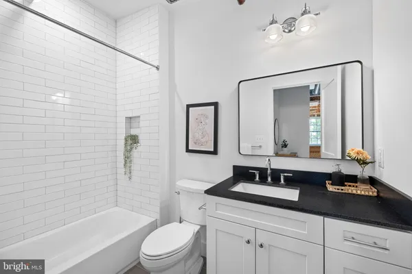 a bathroom with a granite countertop sink a toilet a mirror a vanity a bathtub and shower
