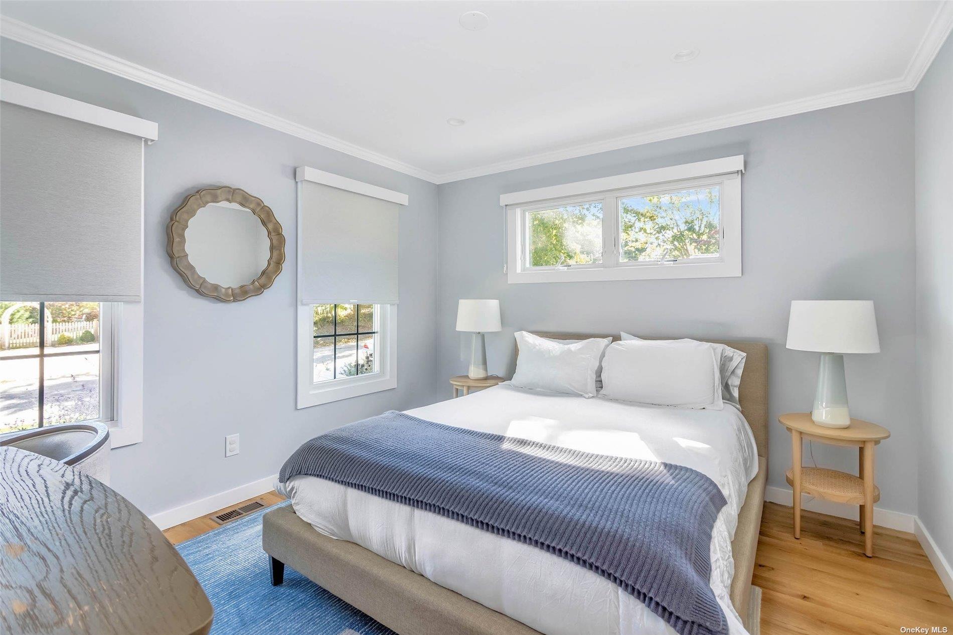 155 Bridge Street Greenport, NY 11944 - Photo 12 of 30 a bedroom with a bed and a lamp with wooden floor