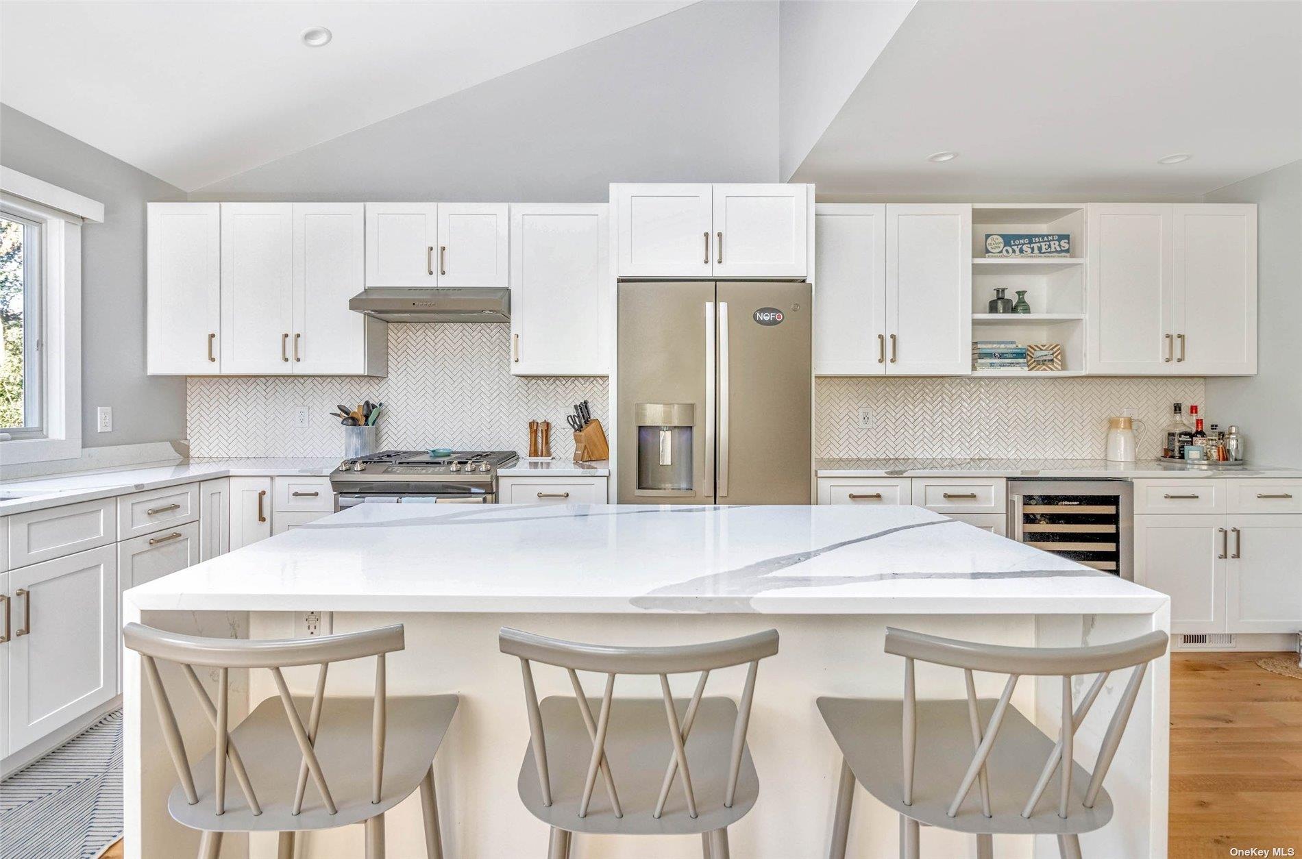 155 Bridge Street Greenport, NY 11944 - Photo 7 of 30 a kitchen with stainless steel appliances a table chairs and a refrigerator