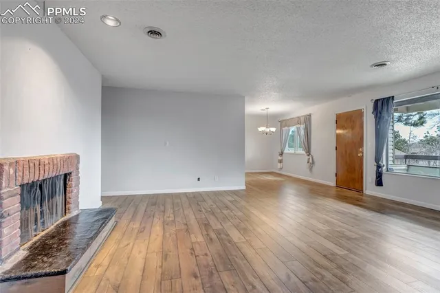 a view of a livingroom with wooden floor and a fireplace
