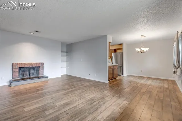 an empty room with wooden floor a fireplace and windows
