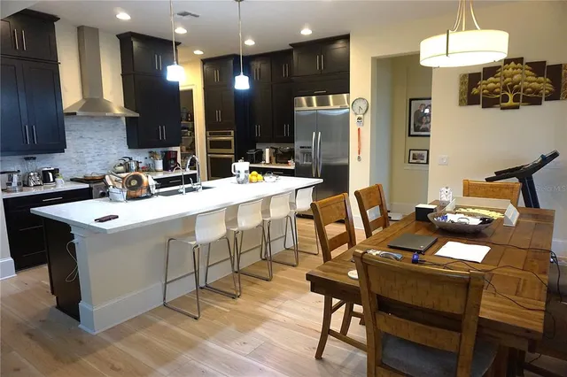 a kitchen with a stove a refrigerator and a dining table with wooden floor