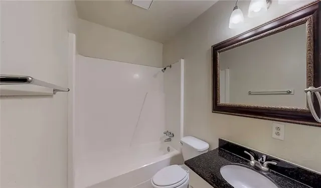 a bathroom with a granite countertop toilet sink and mirror