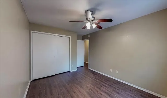 an empty room with wooden floor fan and windows