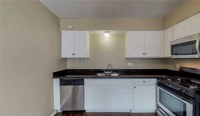a kitchen with granite countertop white cabinets and stainless steel appliances