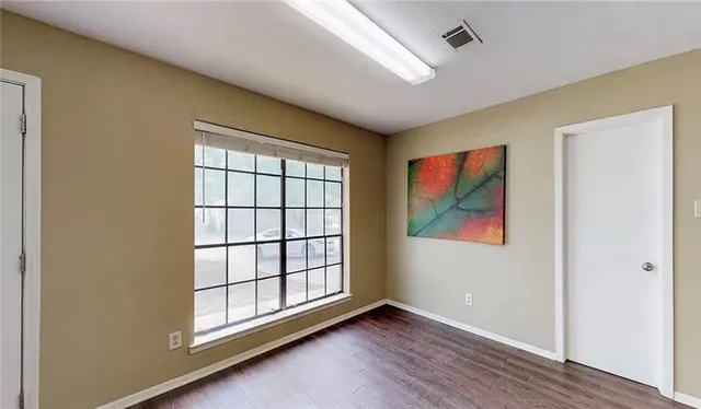 an empty room with wooden floor and window