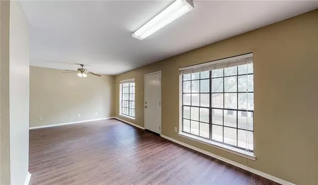 an empty room with wooden floor and windows