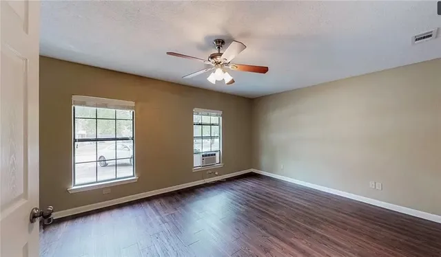 a view of an empty room with window and wooden floor