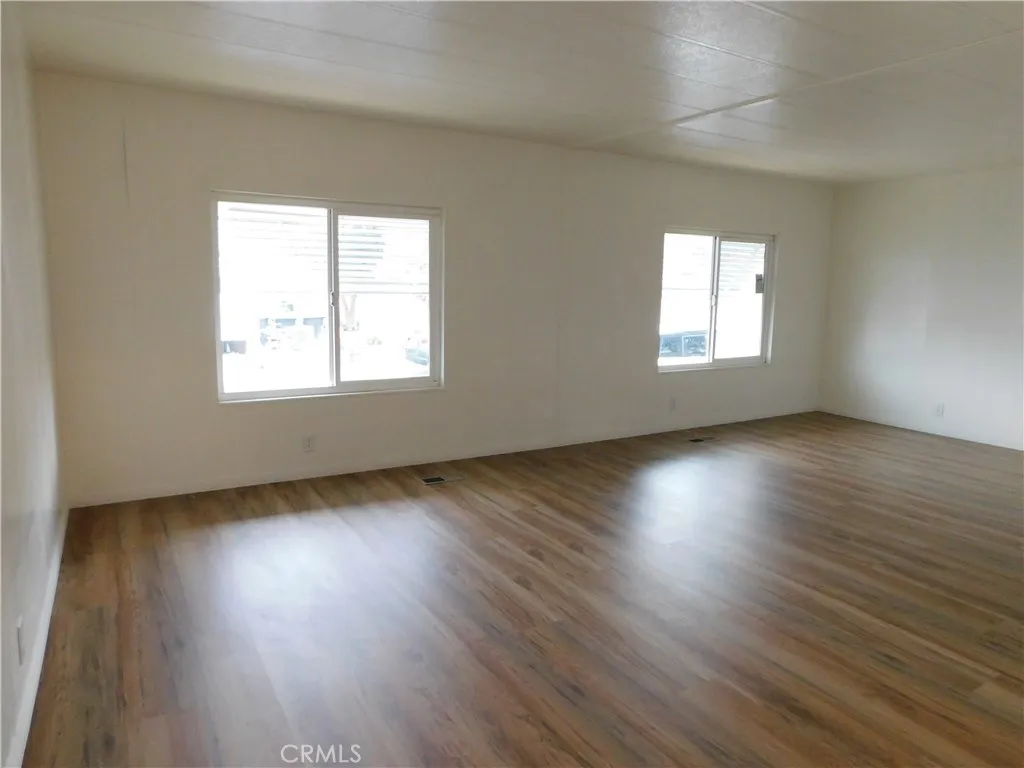 5700 West Wilson Street, Unit 1 Banning, CA 92220 - Photo 7 of 49 an empty room with wooden floor and windows