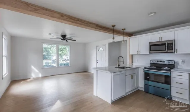 a kitchen with stainless steel appliances granite countertop a stove a sink dishwasher and a microwave oven with white cabinets