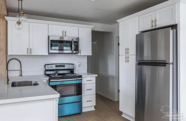 a kitchen with white cabinets stainless steel appliances and a sink