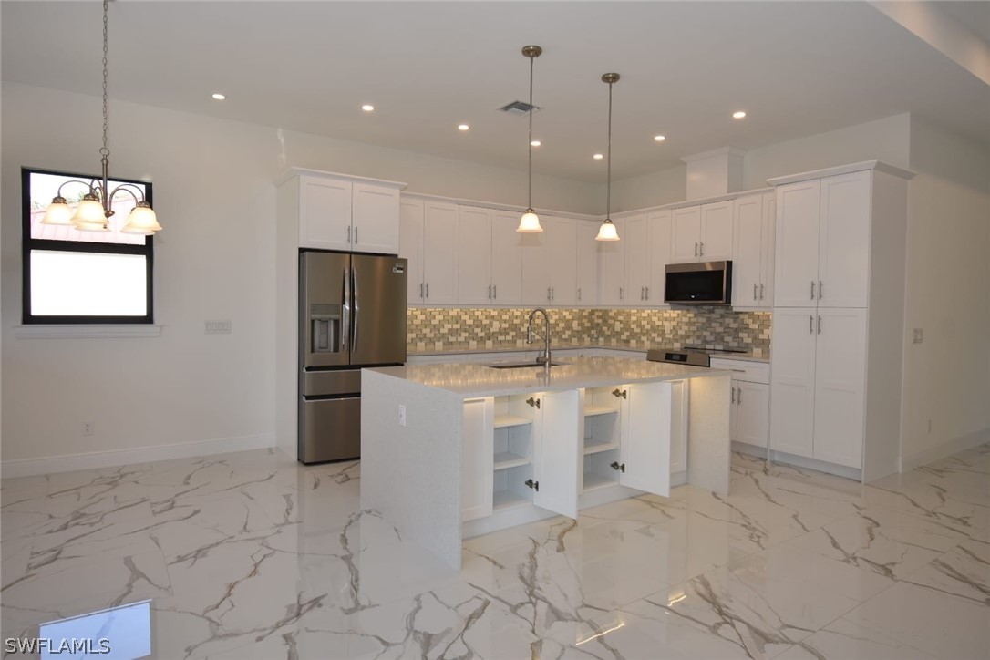 3685 Randall Boulevard Naples, FL 34120 - Photo 12 of 32 a large white kitchen with kitchen island a sink a counter and a refrigerator