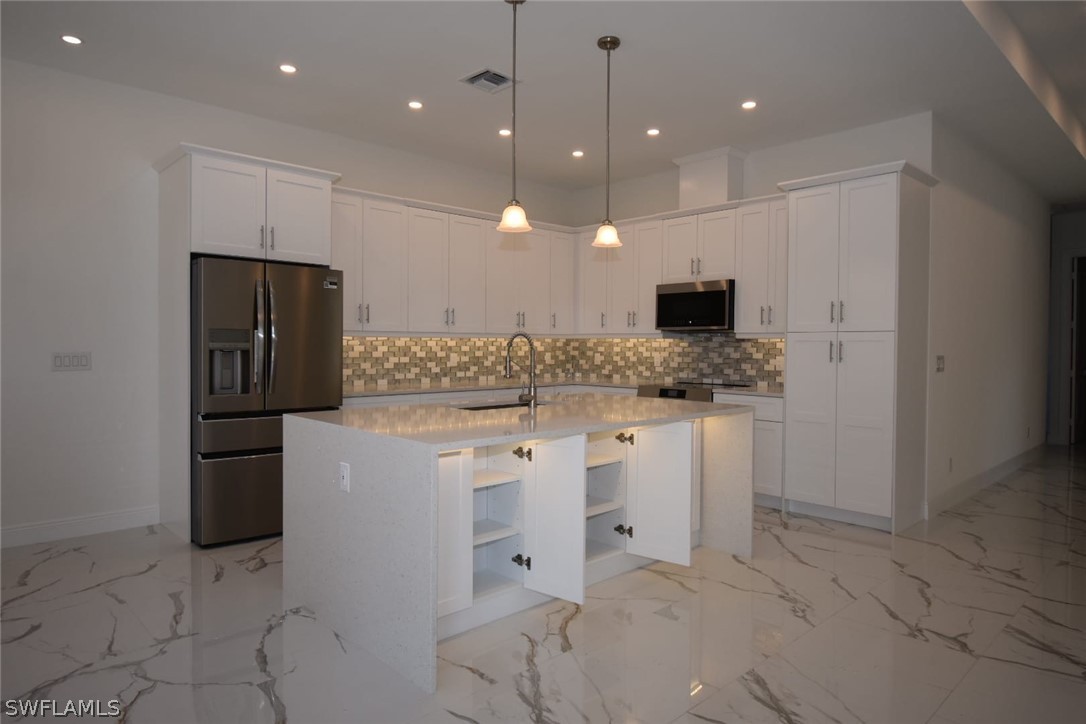 3685 Randall Boulevard Naples, FL 34120 - Photo 30 of 32 a kitchen with white cabinets and stainless steel appliances