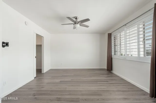 a view of an empty room with wooden floor and a window