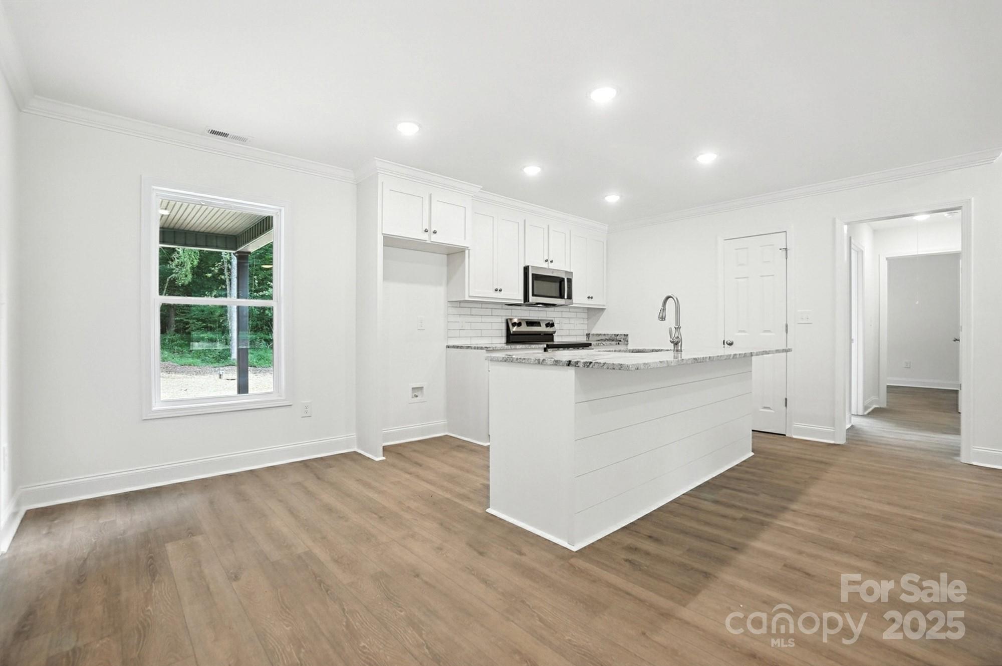 233 Lincoln Road York, SC 29745 - Photo 10 of 37 a large white kitchen with kitchen island a sink wooden floor and a refrigerator