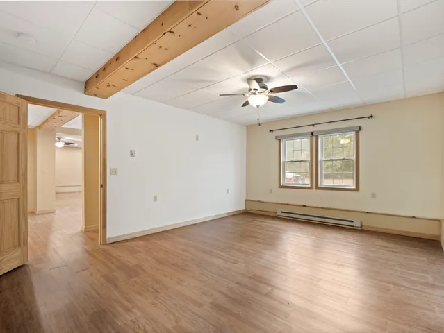 a view of an empty room with a window and wooden floor
