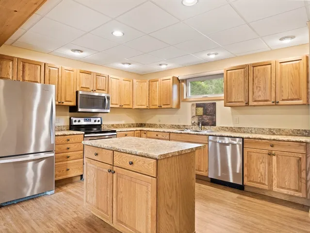 a kitchen with stainless steel appliances granite countertop a refrigerator a sink dishwasher a stove top oven a refrigerator with white cabinets and wooden floor