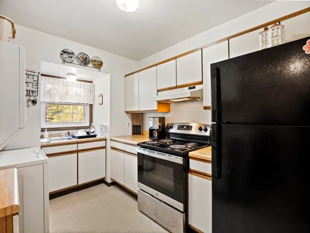 a kitchen with stainless steel appliances granite countertop a refrigerator a sink and white cabinets