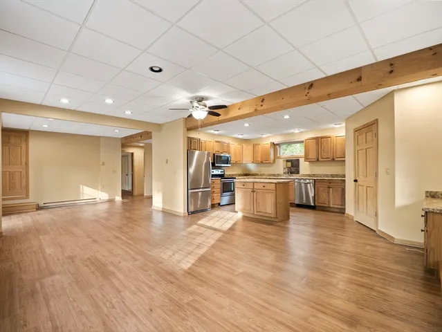 a view of a kitchen with kitchen island a stove a wooden floor and a refrigerator