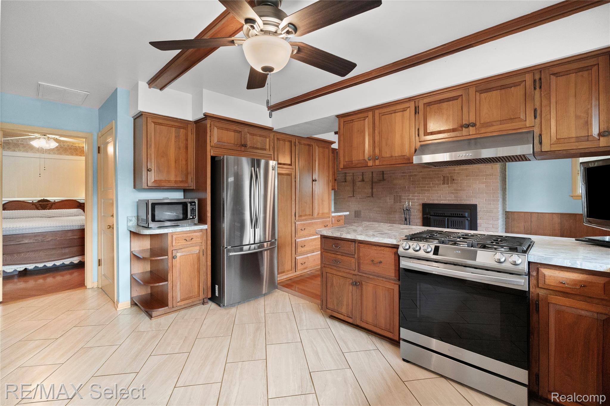 11080 Lapeer Road Davison, MI 48423 - Photo 27 of 64 Kitchen featuring wood cabinetry, stainless steel appliances, a gas range, solid surface countertops, and tile flooring