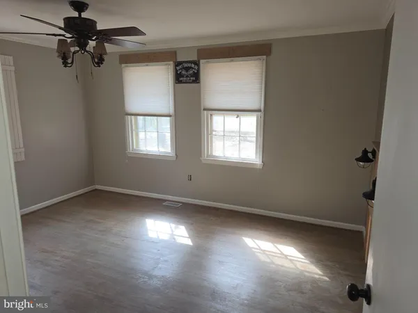 an empty room with windows and fan