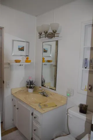 a bathroom with a granite countertop sink a toilet and a mirror