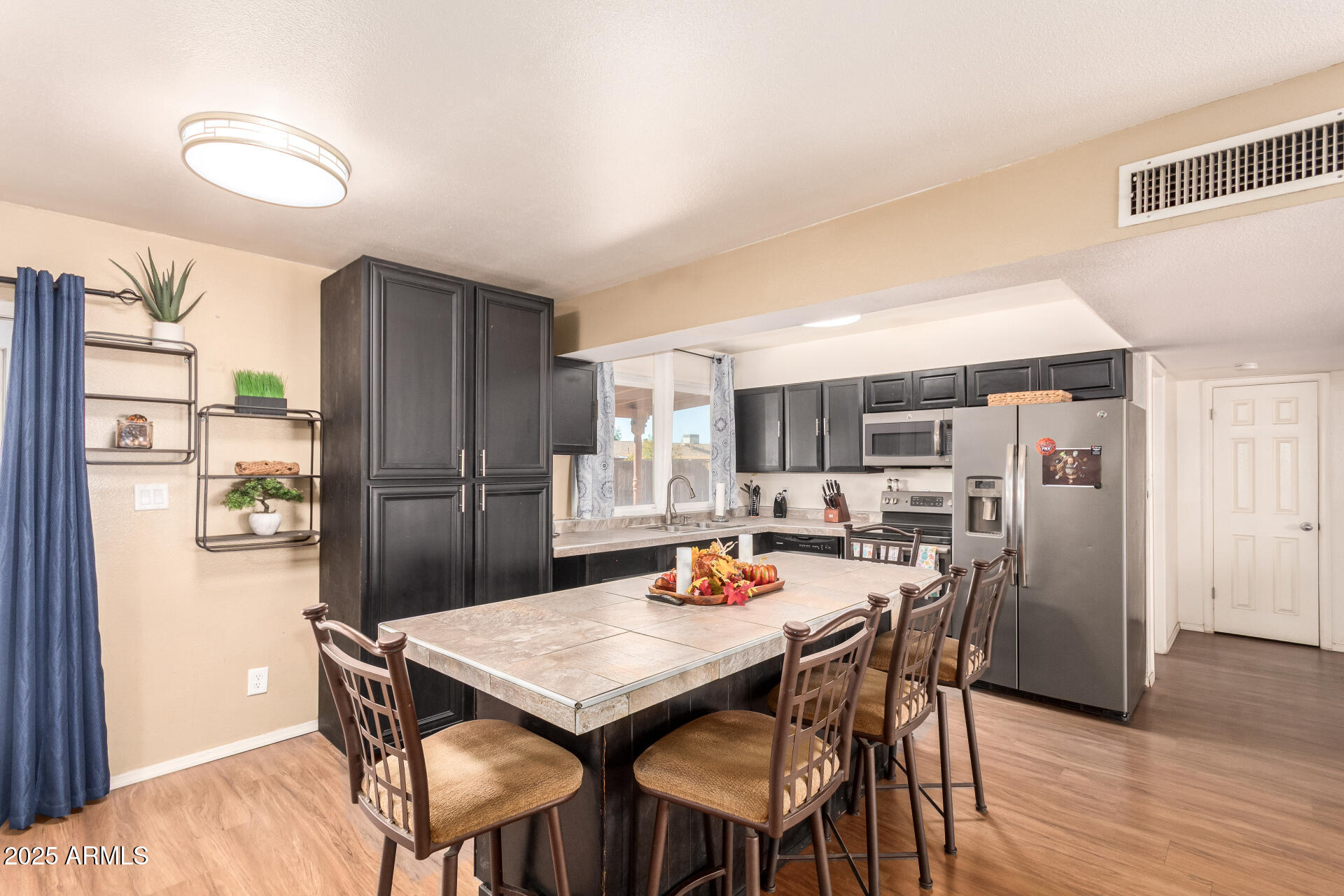 3341 West Pershing Avenue Phoenix, AZ 85029 - Photo 16 of 36 a kitchen with stainless steel appliances a dining table chairs refrigerator and a window