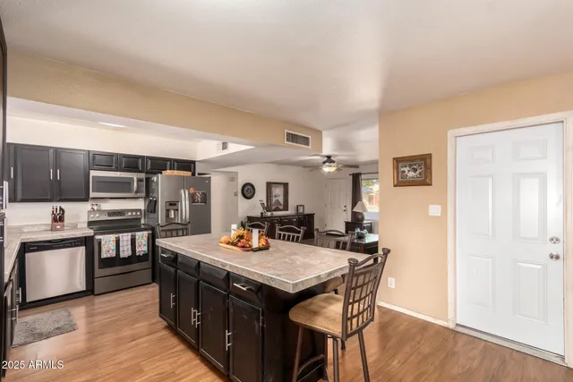 a kitchen with stainless steel appliances kitchen island granite countertop a stove a sink dishwasher and a refrigerator with wooden floor